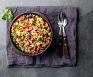 Quinoa and Greens in a bowl on a placemat with garnish and silverware.